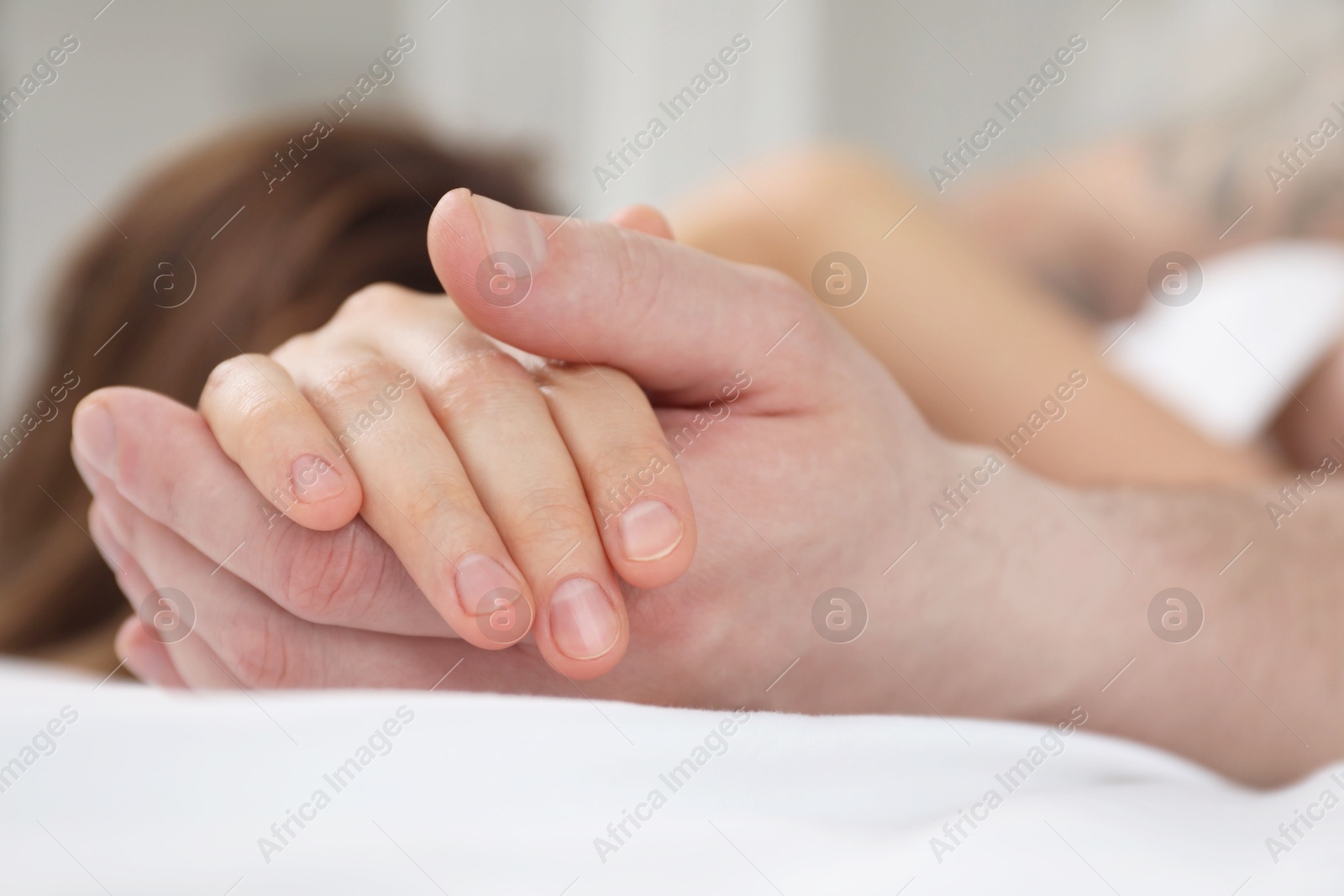 Photo of Lovely couple holding hands in bed, closeup