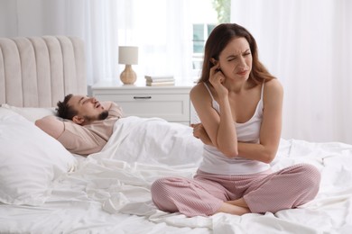 Bedtime. Irritated woman near her snoring husband in bed at home