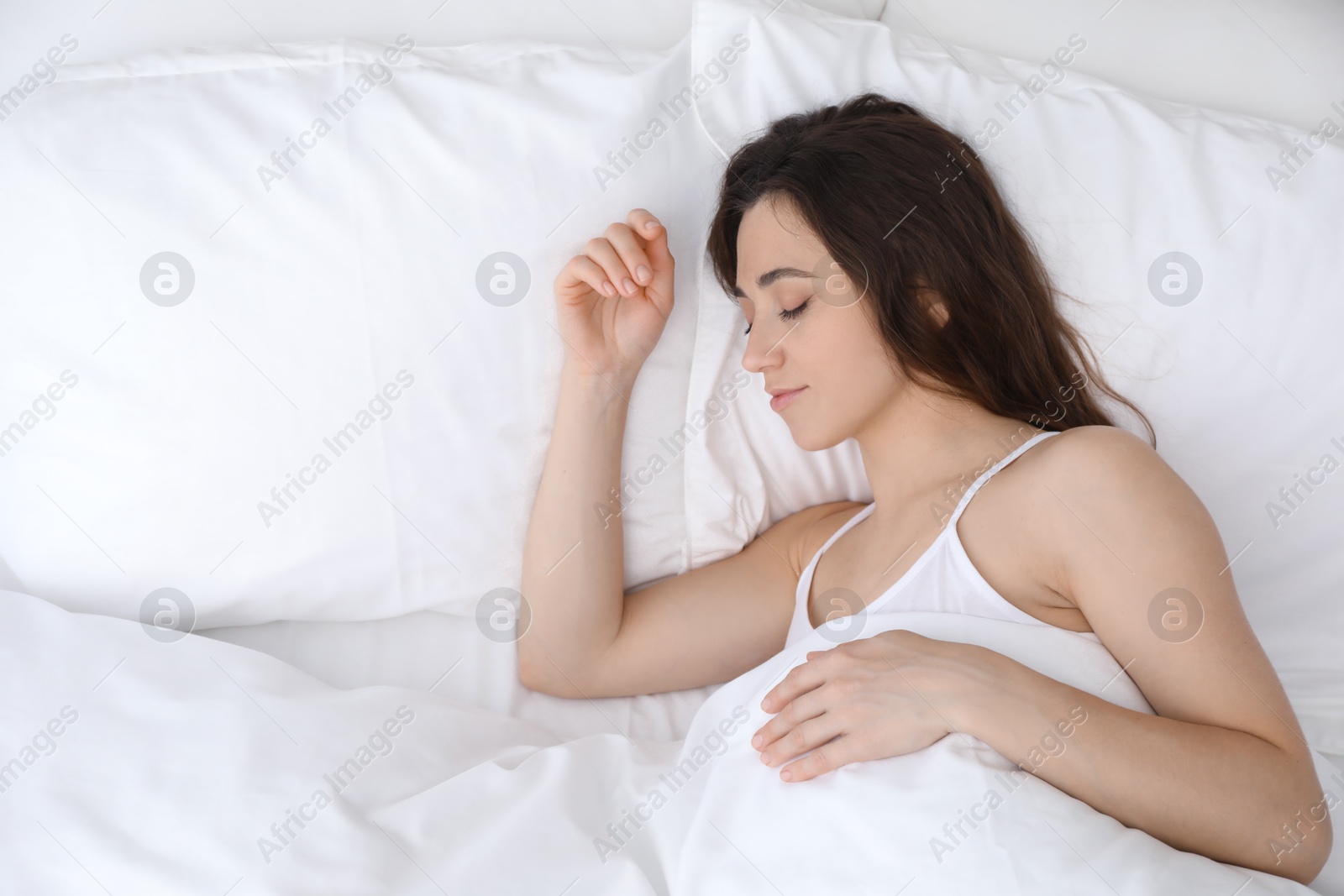 Photo of Bedtime. Beautiful woman sleeping in bed at morning, top view. Space for text