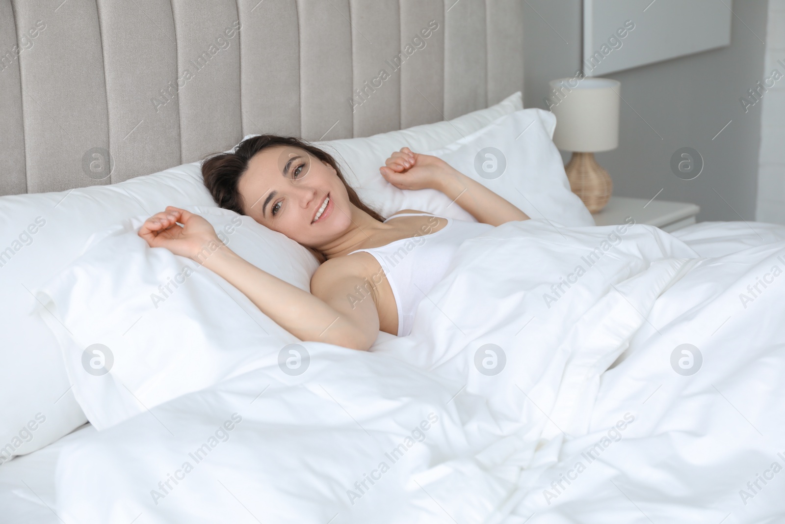 Photo of Smiling woman lying in bed at morning