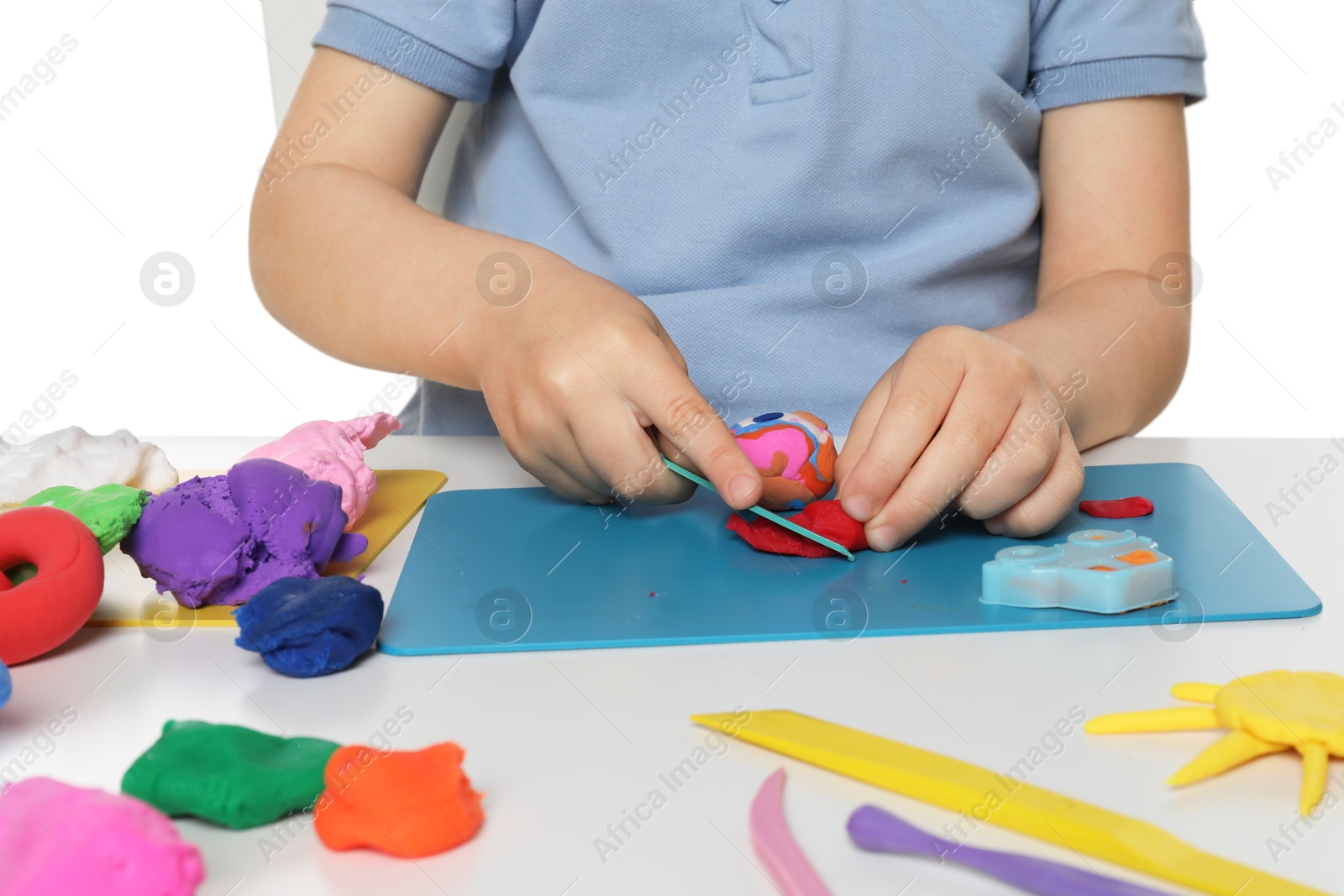 Photo of Little boy sculpting with play dough at table on white background, closeup