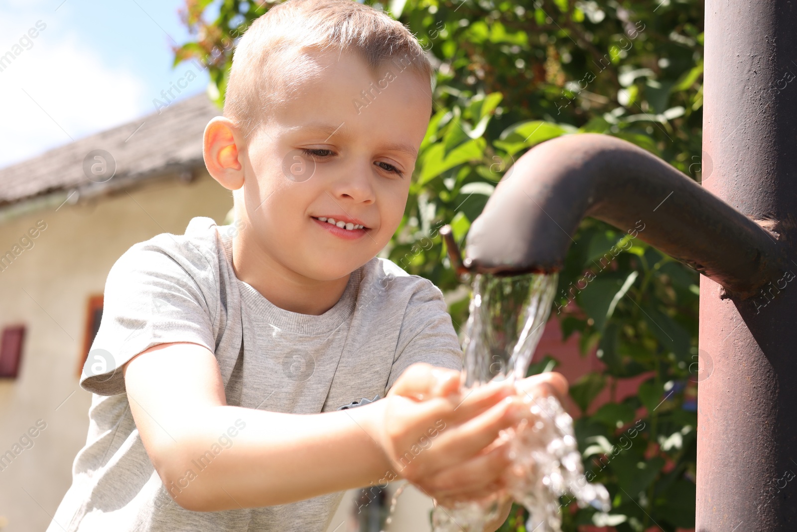 Photo of Water scarcity. Cute little boy drinking water from tap outdoors