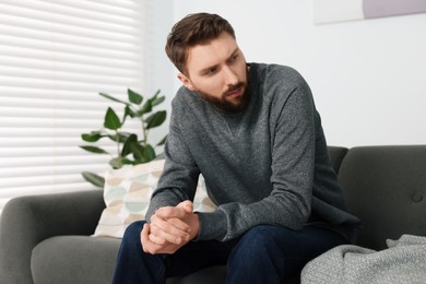 Photo of Loneliness concept. Sad man sitting on sofa at home