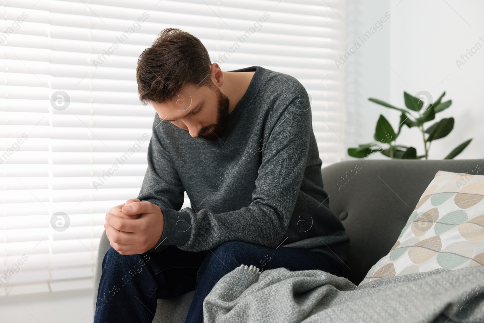 Photo of Loneliness concept. Sad man sitting on sofa at home