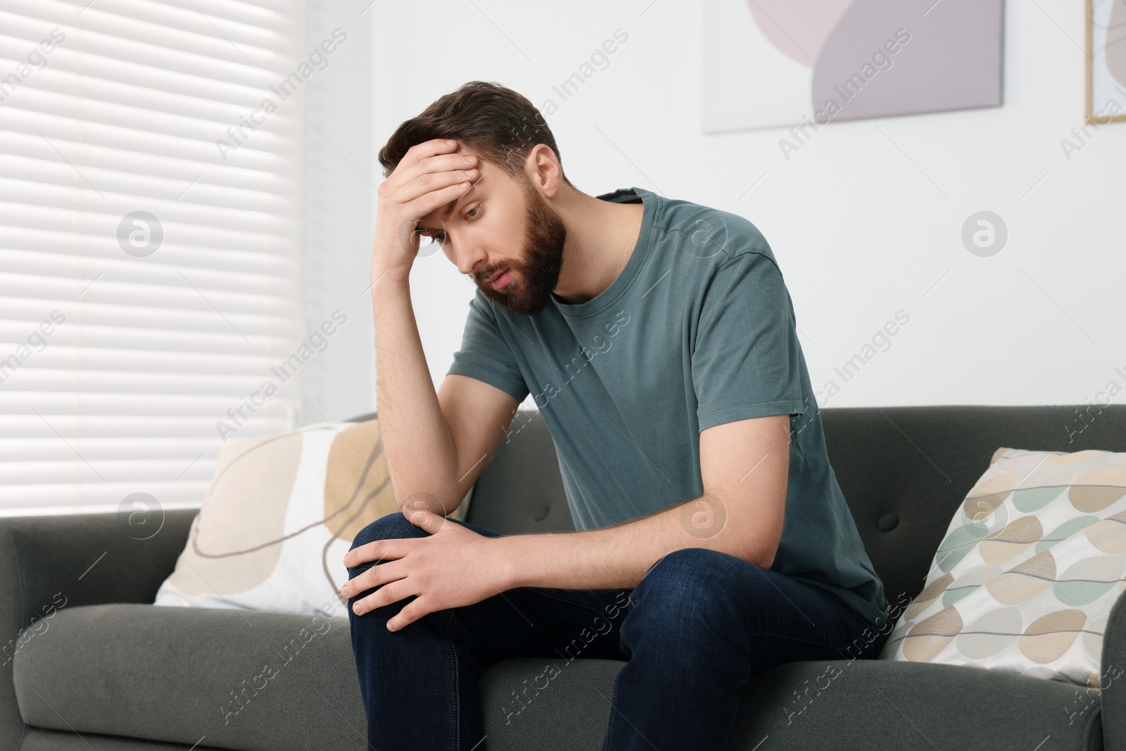 Photo of Loneliness concept. Sad man sitting on sofa at home