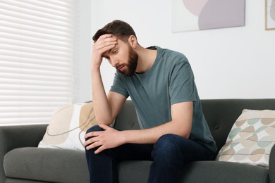 Photo of Loneliness concept. Sad man sitting on sofa at home