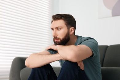 Photo of Loneliness concept. Sad man sitting on floor at home