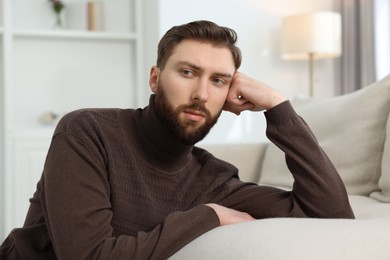 Photo of Loneliness concept. Sad man sitting on sofa at home