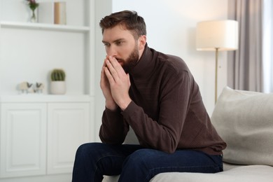 Loneliness concept. Sad man sitting on sofa at home