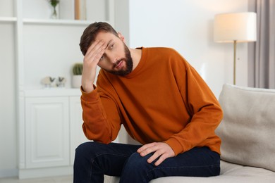 Photo of Loneliness concept. Sad man sitting on sofa at home