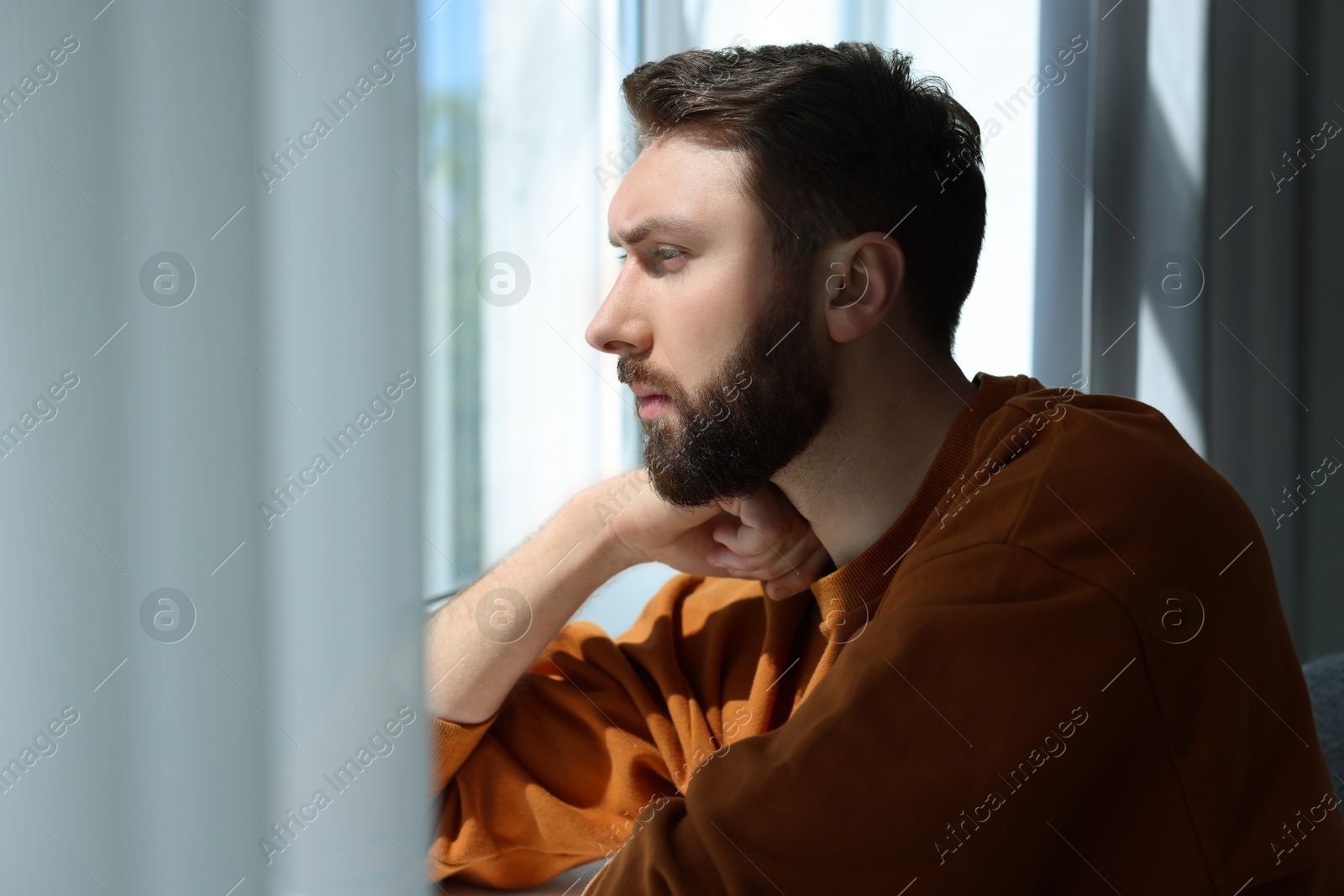 Photo of Loneliness concept. Sad man near window at home