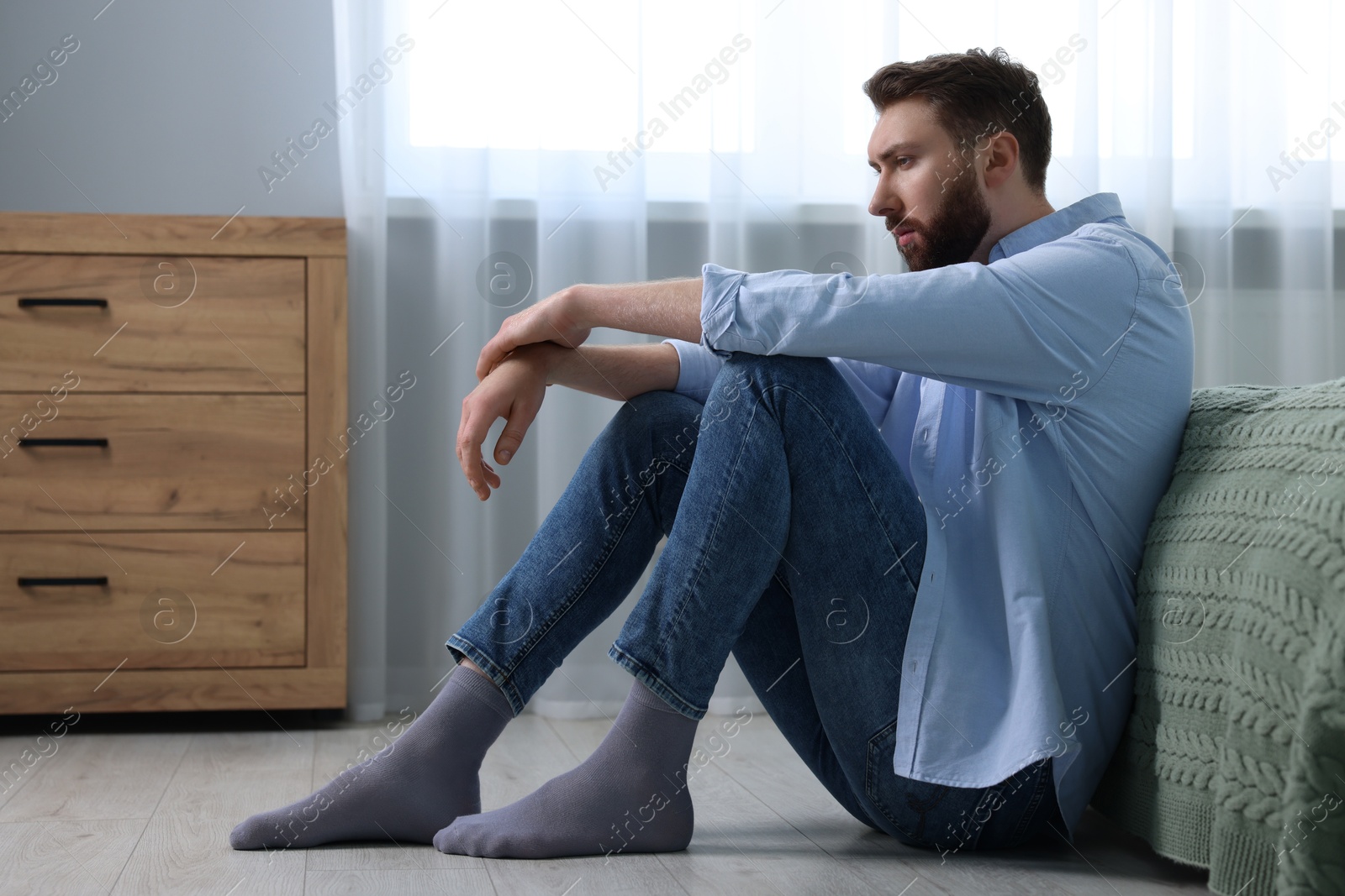 Photo of Loneliness concept. Sad man sitting on floor at home