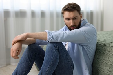 Photo of Loneliness concept. Sad man sitting on floor at home