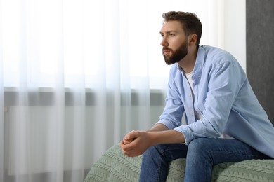 Photo of Loneliness concept. Sad man sitting on bed at home, space for text