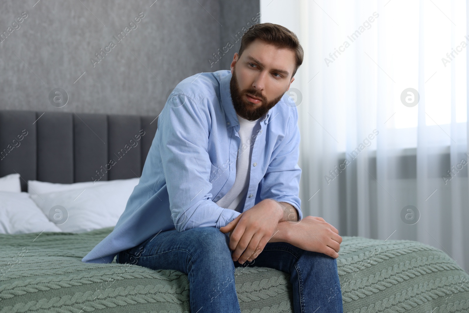 Photo of Loneliness concept. Sad man sitting on bed at home