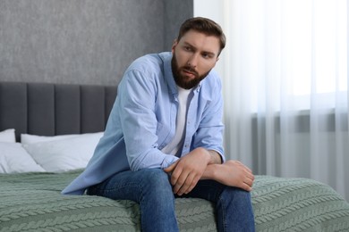 Photo of Loneliness concept. Sad man sitting on bed at home