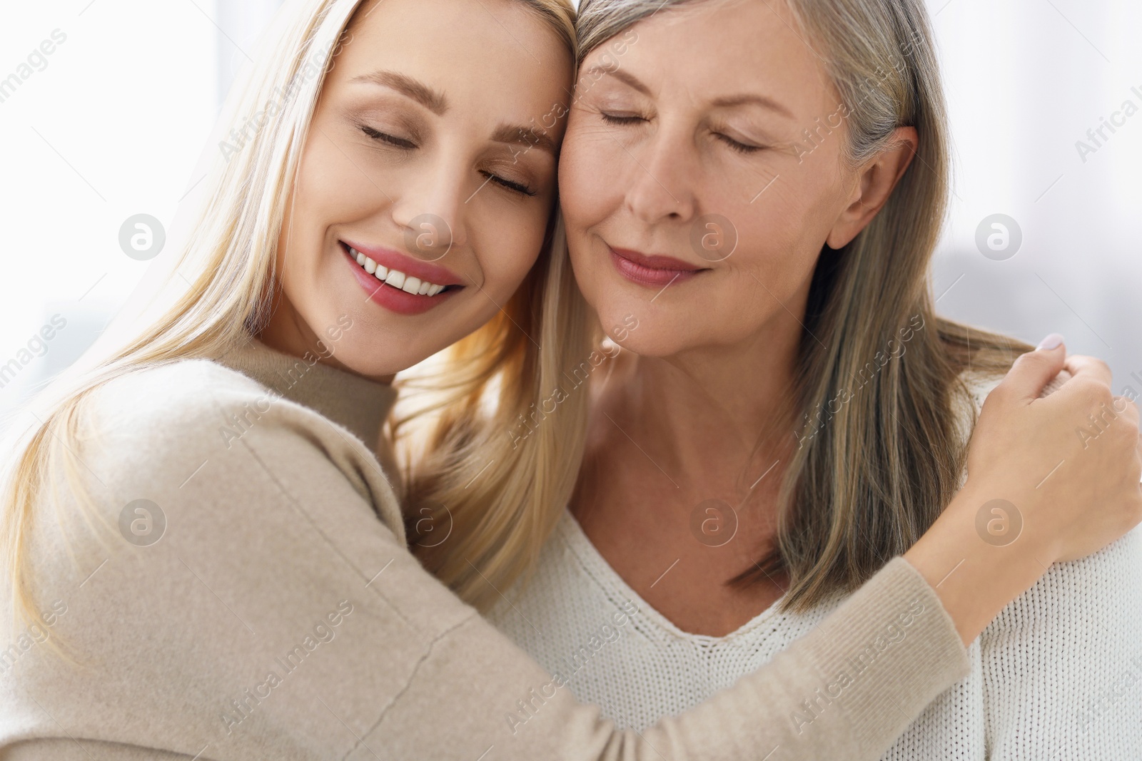 Photo of Family portrait of young woman and her mother on light background