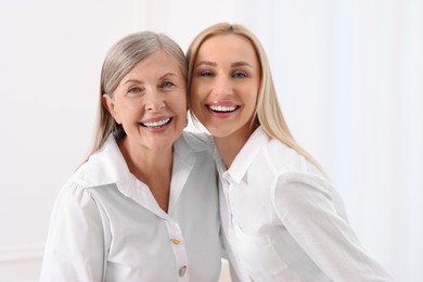 Family portrait of young woman and her mother on white background