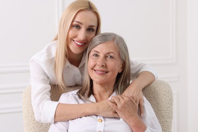 Family portrait of young woman and her mother near white wall