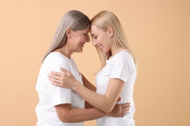 Photo of Family portrait of young woman and her mother on beige background