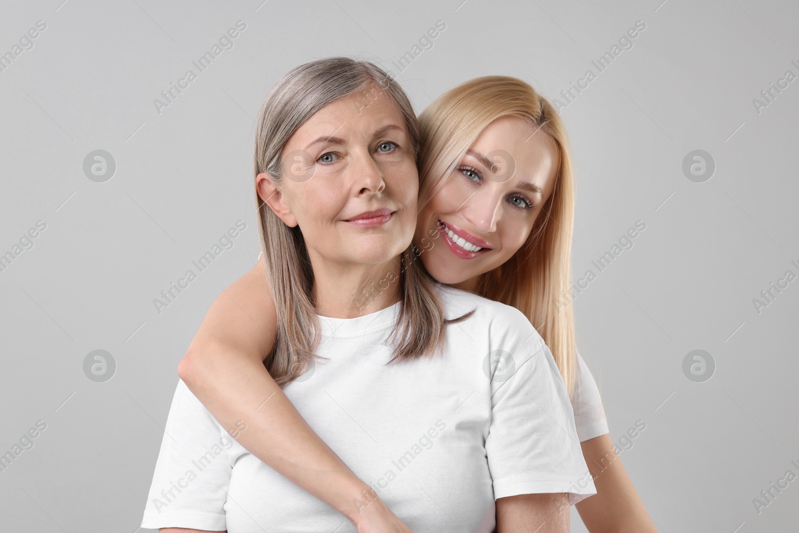 Photo of Family portrait of young woman and her mother on light grey background