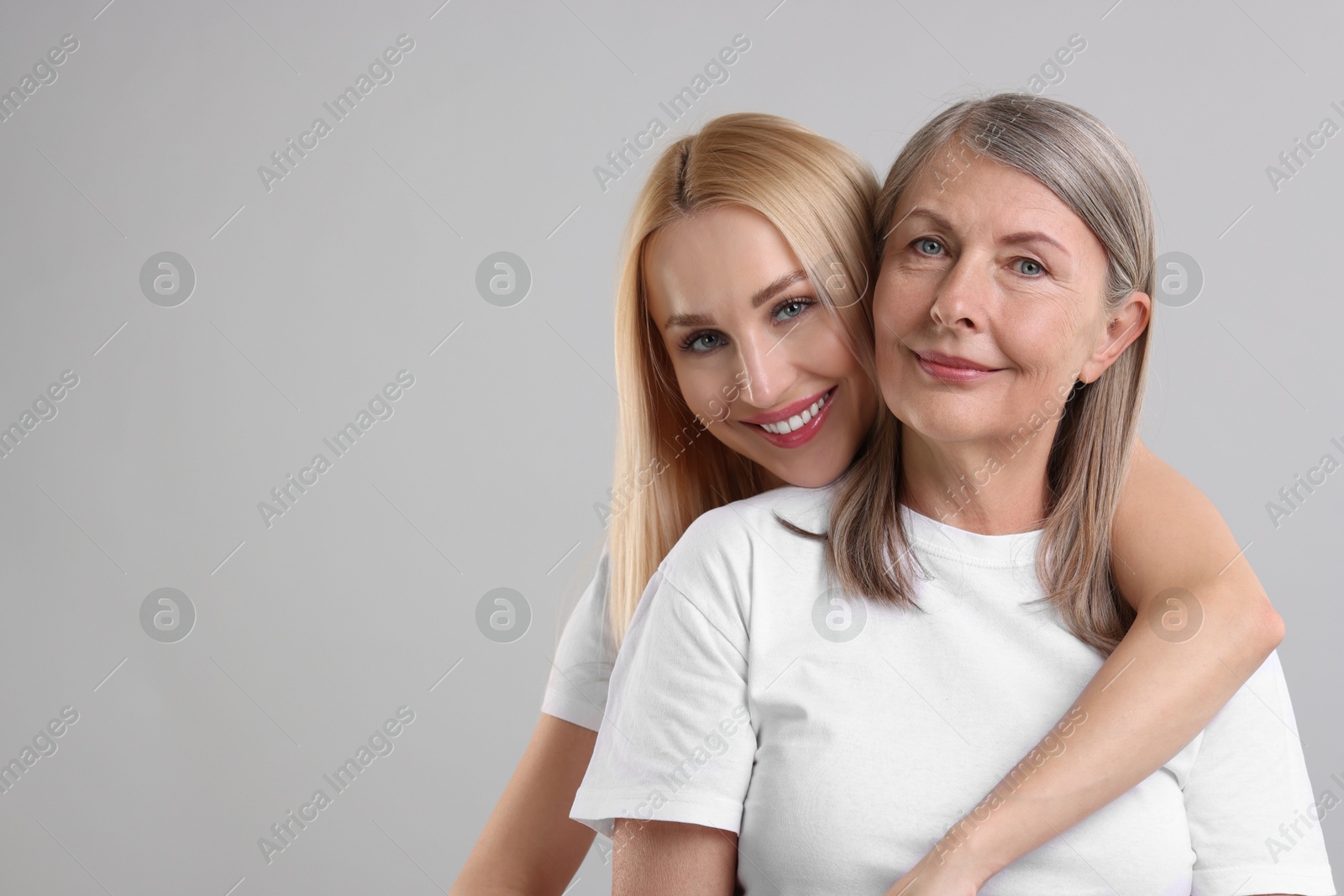 Photo of Family portrait of young woman and her mother on light grey background. Space for text