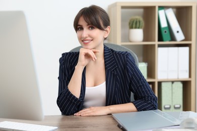 Portrait of smiling secretary at table in office