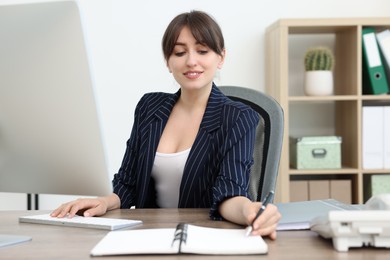 Photo of Smiling secretary working at table in office