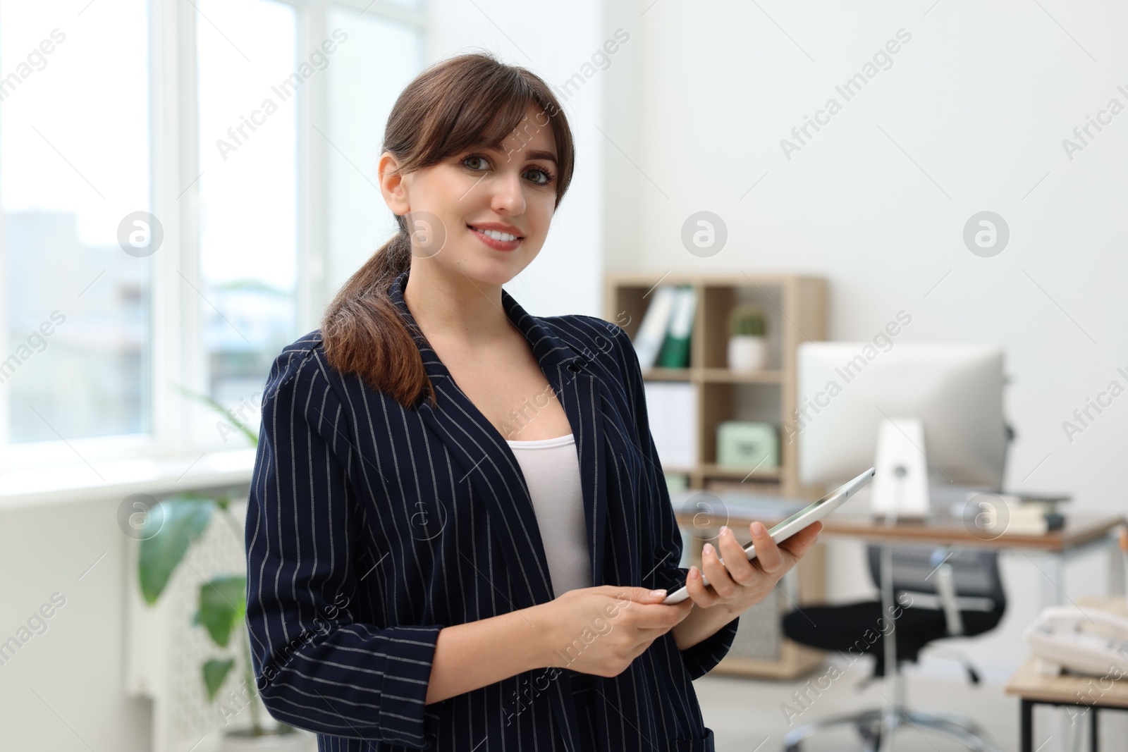 Photo of Portrait of smiling secretary with tablet in office