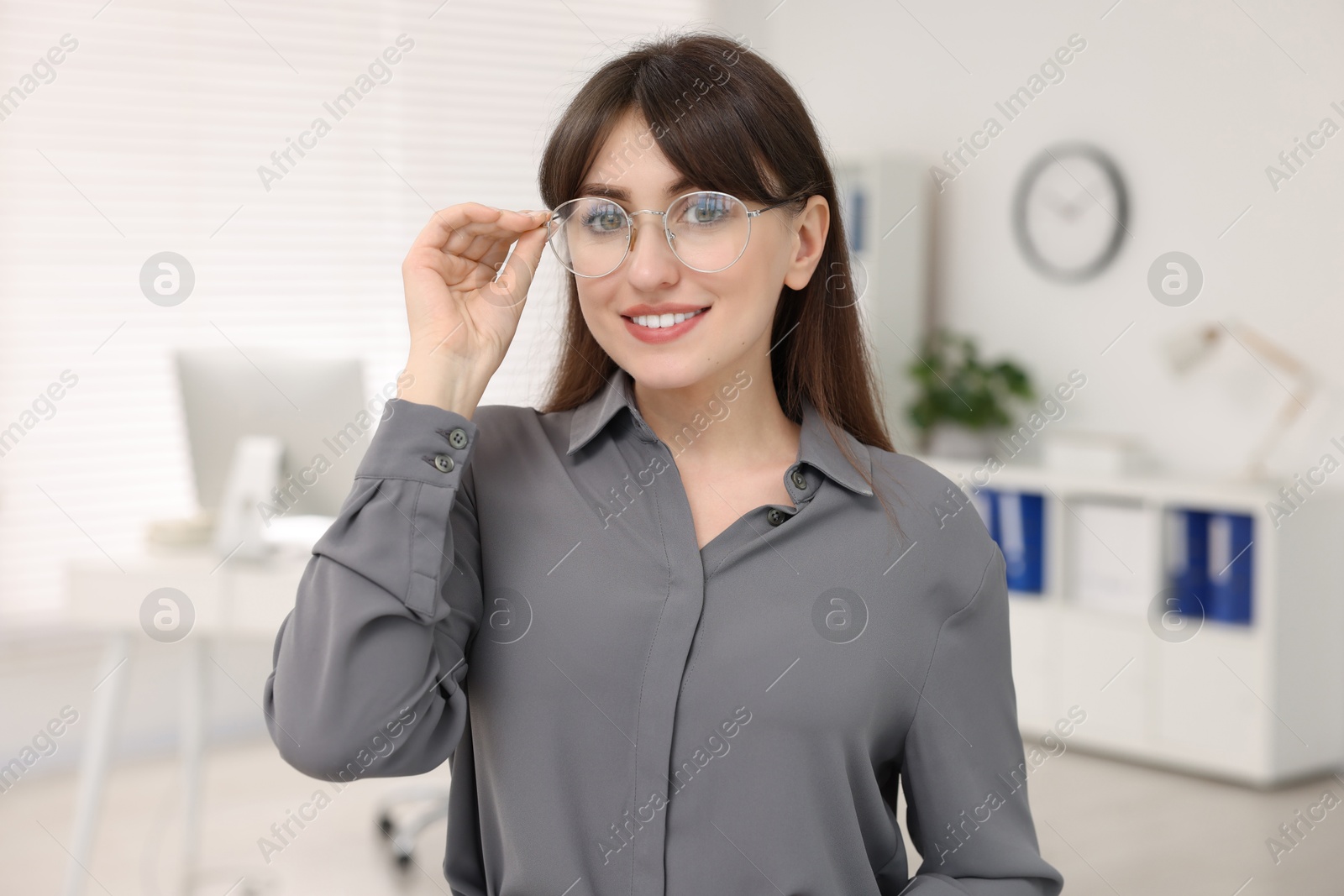 Photo of Portrait of smiling secretary wearing glasses in office