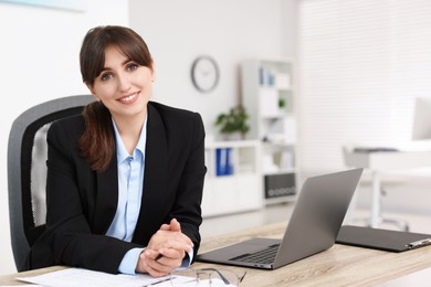 Portrait of smiling secretary at table in office