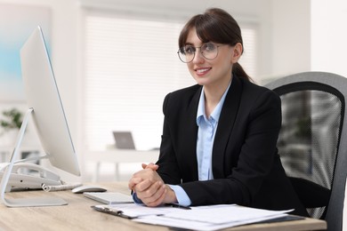 Portrait of smiling secretary at table in office