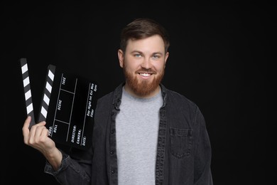 Making movie. Smiling man with clapperboard on black background