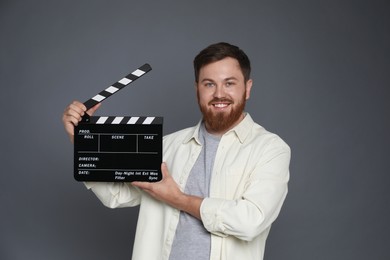 Photo of Making movie. Smiling man with clapperboard on grey background
