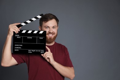 Photo of Making movie. Smiling man with clapperboard on grey background. Space for text