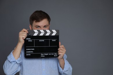 Photo of Making movie. Man with clapperboard on grey background. Space for text