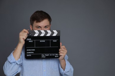 Making movie. Man with clapperboard on grey background. Space for text