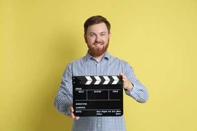 Photo of Making movie. Smiling man with clapperboard on yellow background