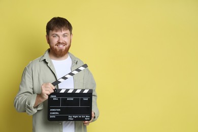 Photo of Making movie. Smiling man with clapperboard on yellow background. Space for text