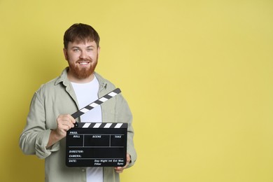 Making movie. Smiling man with clapperboard on yellow background. Space for text