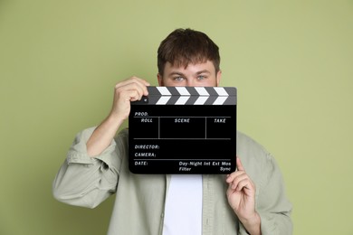 Photo of Making movie. Man with clapperboard on green background
