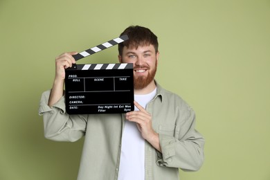 Photo of Making movie. Smiling man with clapperboard on green background