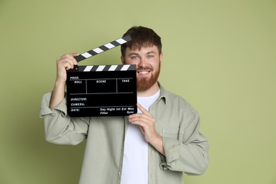 Making movie. Smiling man with clapperboard on green background