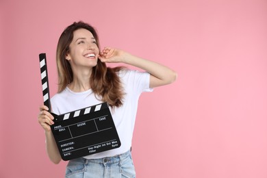 Photo of Making movie. Smiling woman with clapperboard on pink background. Space for text