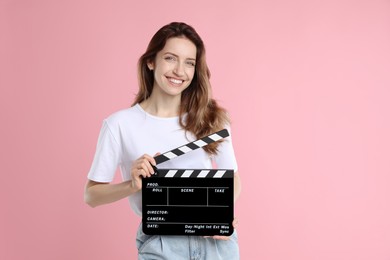 Making movie. Smiling woman with clapperboard on pink background