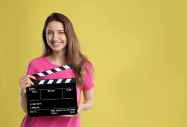 Making movie. Smiling woman with clapperboard on yellow background. Space for text