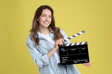 Photo of Making movie. Smiling woman with clapperboard on yellow background
