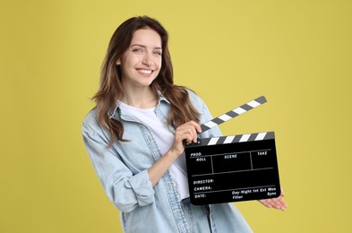 Making movie. Smiling woman with clapperboard on yellow background