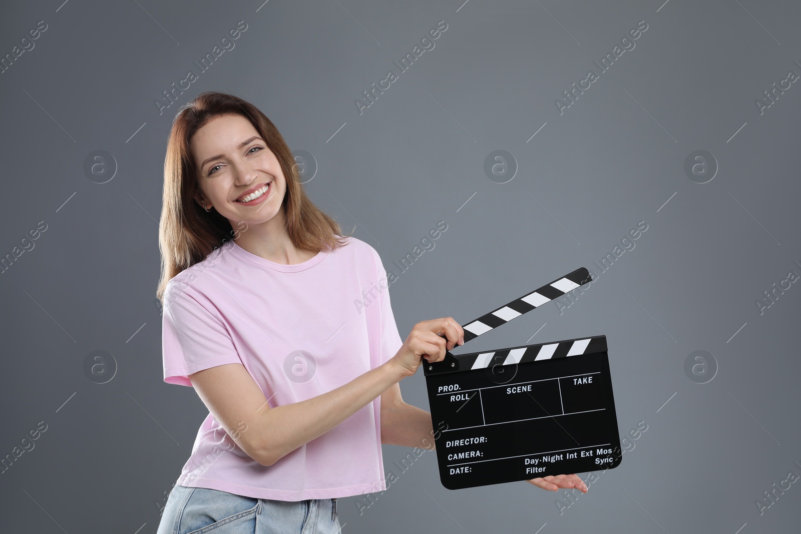 Photo of Making movie. Smiling woman with clapperboard on grey background