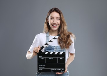 Photo of Making movie. Smiling woman with clapperboard on grey background